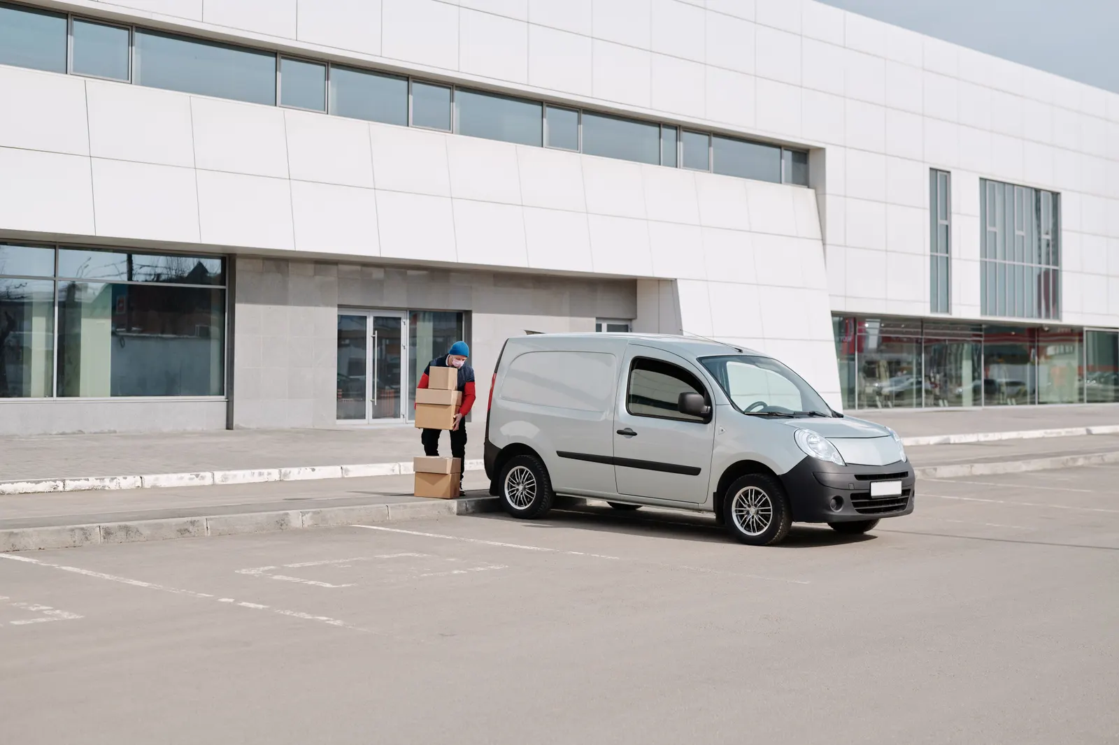 Courier loading parcels into a delivery van outside a depot