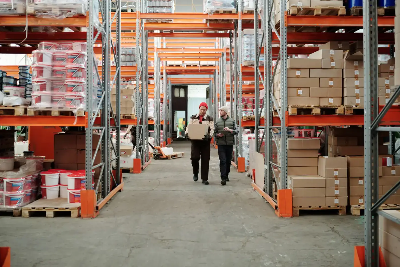Two warehouse operators walking a parcel through racking